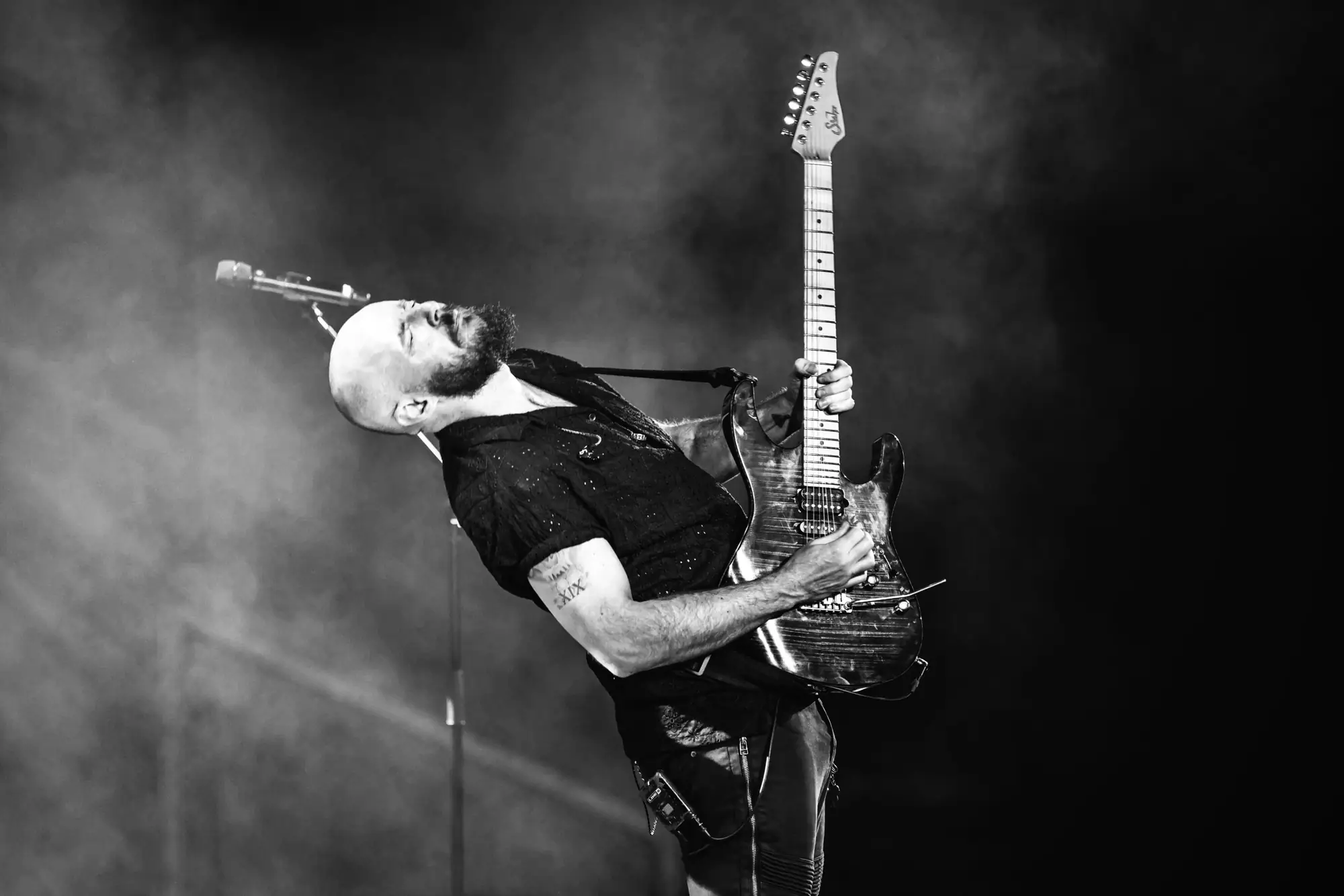 Ben Hartwell playing guitar live on stage, head thrown back, in black and white