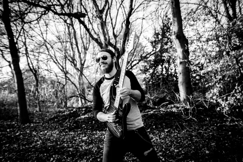 Ben playing guitar among trees, black and white